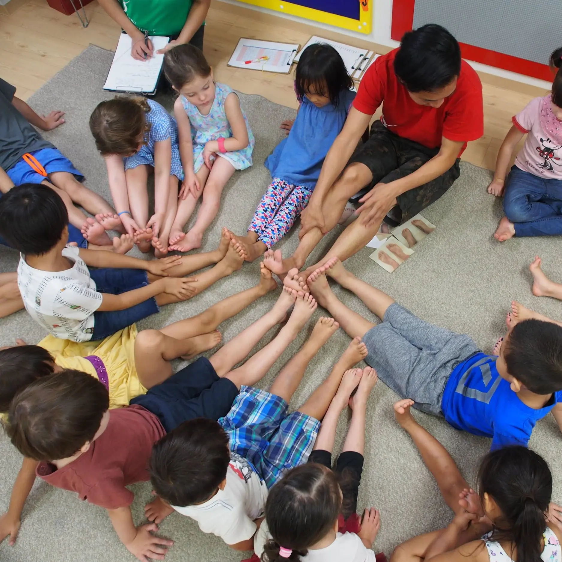 Children sitting on the floor while doing stretches at Ohana International School